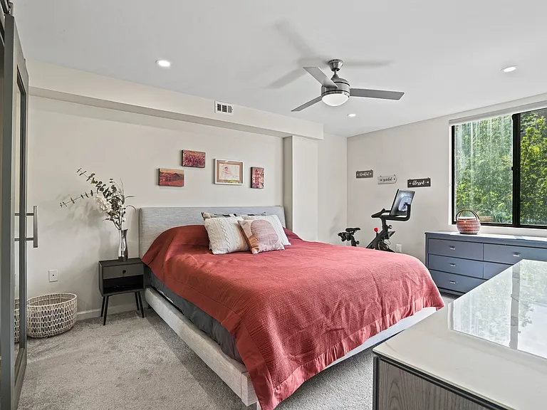 Spacious primary suite featuring high ceilings, plush carpeting, abundant natural light, and private balcony access.