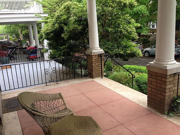 View from large covered porch looking onto tree-lined street.
