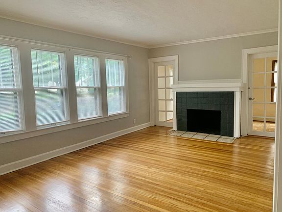 Large living room with lots of natural light. View of bonus room behind the fireplace which is a great office, workout, or studio space. Beautiful hardwood floors throughout the apartment.