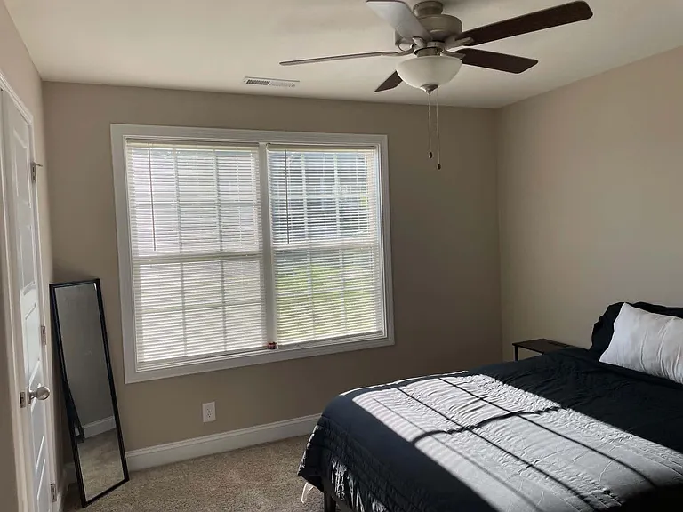 Comfortable bedroom with a large window, ceiling fan, and space for a full bed plus small nightstand or dresser.