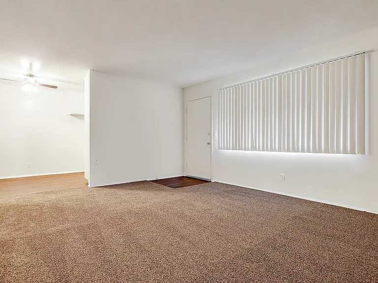 Living room with carpeted floors, wood style floors in dining area with ceiling fan