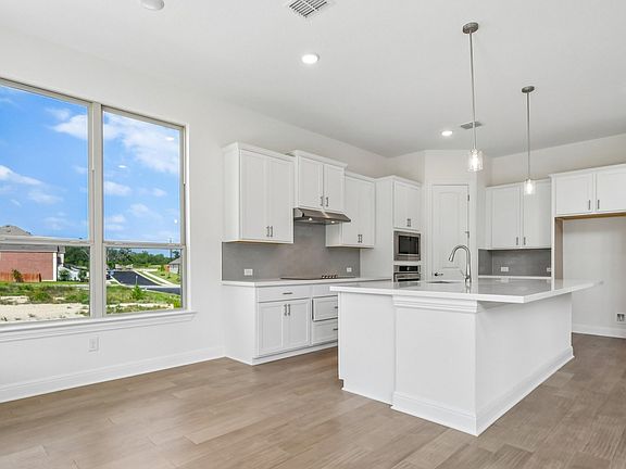 An interior shot of the dining area and kitchen in the Brown floorplan at Retreat at San Gabriel - R
