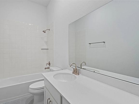 Stylish secondary bath with a shower tub combo and a large vanity featuring white cabinets and light