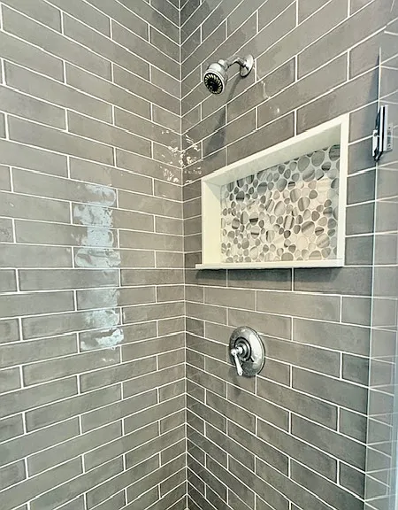 stand up shower has handy built in shelf + broad gray subway tiles.