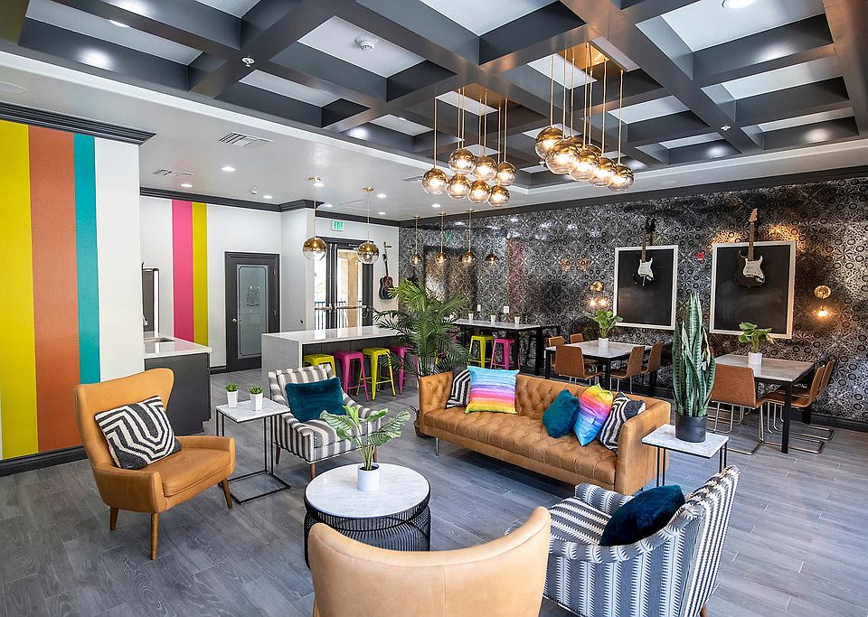 Clubhouse with a TV, a fireplace, a sofa, tables, chairs, a breakfast bar, and a kitchen with stainless steel appliances.