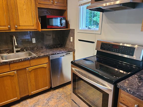 Electric stove, dishwasher, and microwave nook.