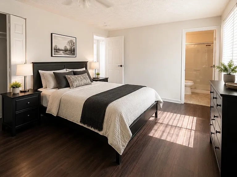 Spacious furnished bedroom with dark wood floors, dresser storage, and an en-suite bath for added convenience.
