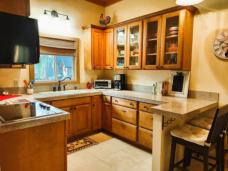 Modern Kitchen with Window over Sink & High Quality Appliances: Convection Microwave, Glass Stovetop, Oversized Refrigerator, Toaster Oven, Electric Tea Kettle, Glass Cabinet Doors, Breakfast Bar & Stools & a vast assortment of Kitchenware, etc.
