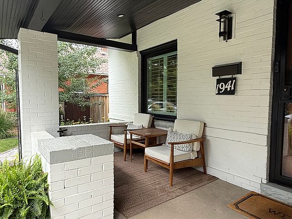 Enjoy this serene front porch seating area with teak chairs, table and carpet.