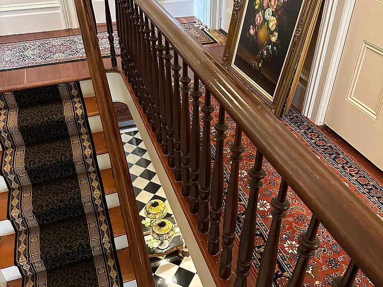 Looking down to the entry hall and marble checkerboard floor. Original railing.