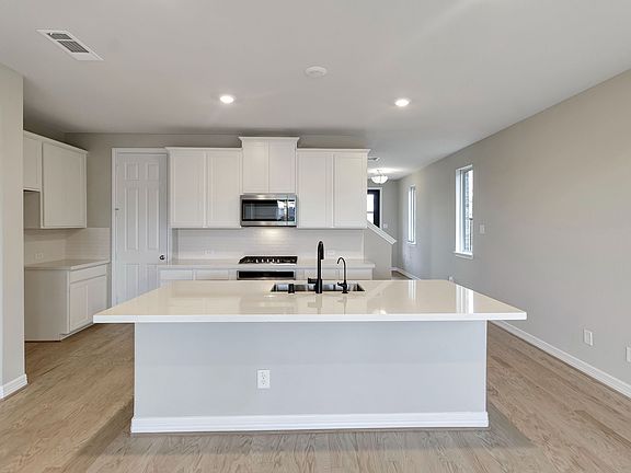 Kitchen featuring white cabinetry, quartz countertops and a modern tile backsplash