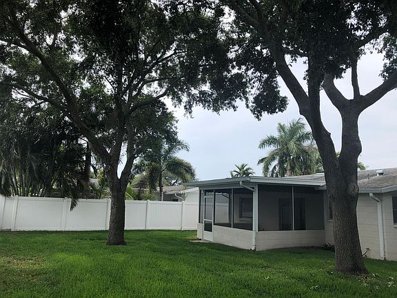 Back of house with large shade trees.