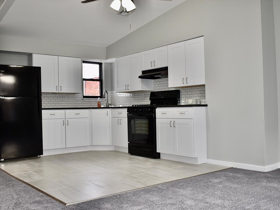View of the kitchen from the living room area. The entire kitchen is brand new. It has ample lighting from the ceiling fan and the LED fixture above the sink.