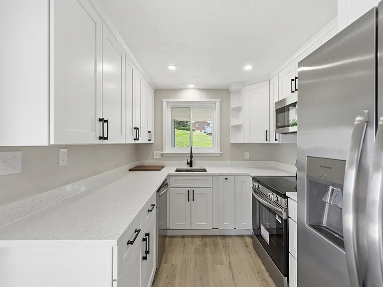 Renovated kitchen with stainless steel appliances, garbage disposal, quartz counters, undermount sink with custom inserts, soft-close drawers/door, and LED lighting.