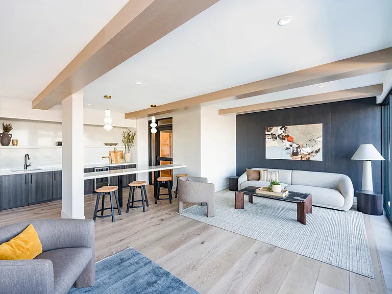 Spacious resident lounge with warm wood accents, comfortable seating, and a sleek entertaining bar.