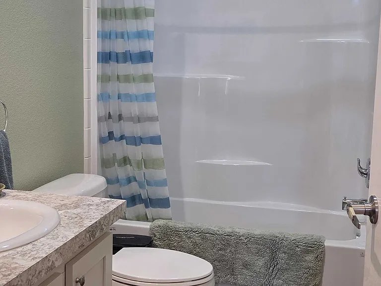 Full private bathroom with tub/shower combination and an opening window above shower for ventilation and light.