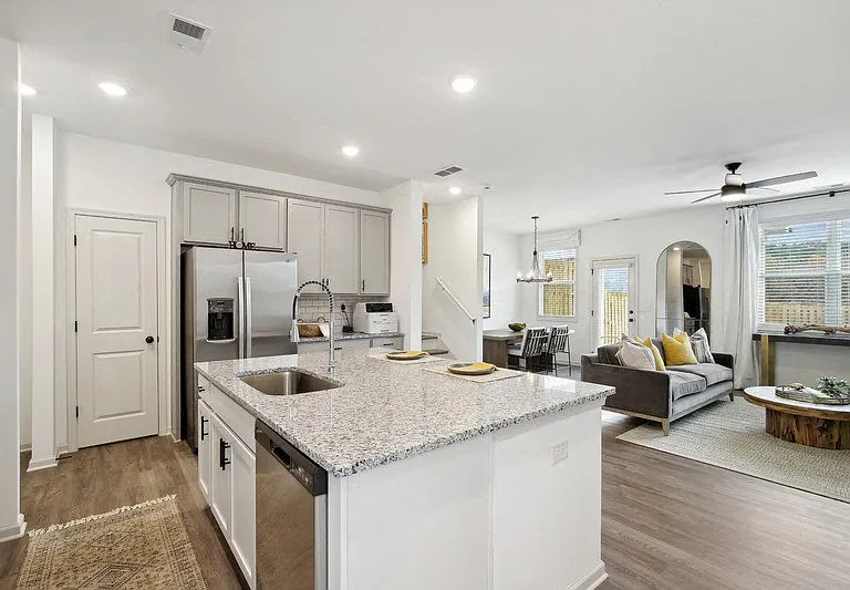 Spacious kitchen with an island, ample storage, stainless steel appliances and view into the living room.