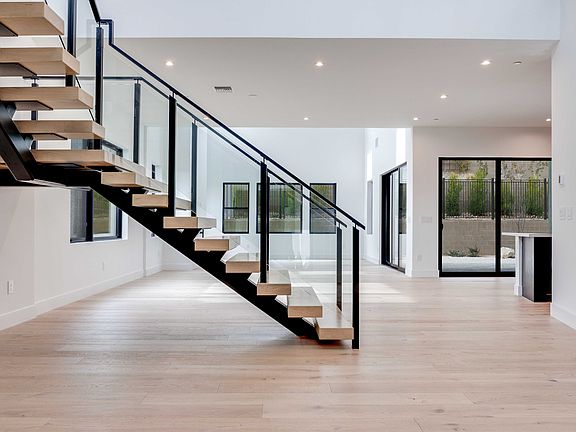 A modern, open-concept interior with a sleek, black metal staircase leading up to a second level, su