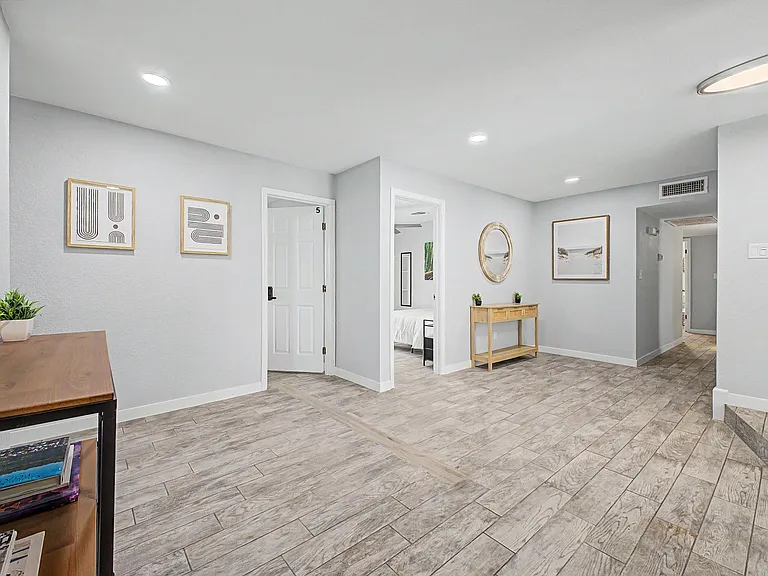 Wide hallway/common area with durable tile flooring, recessed lighting, and easy access to nearby bedrooms and baths.