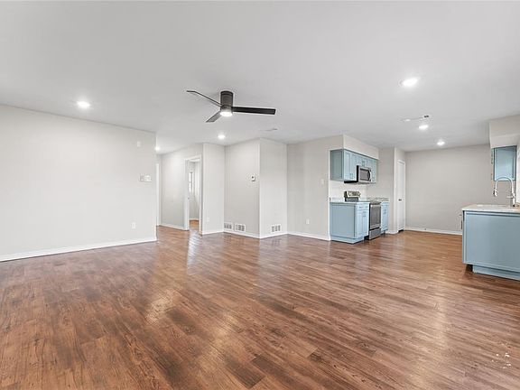 Unfurnished living room featuring ceiling fan, sink, and dark wood-type flooring