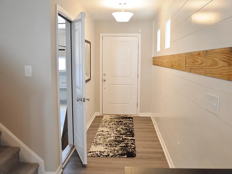 This view is looking towards the front door with the garage on the left. The ship lap designer wall on the right extends down the length of the room.