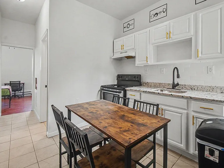 Eat-in kitchen with white cabinetry, granite-look counters, tile backsplash, and a full-size range plus dining table.