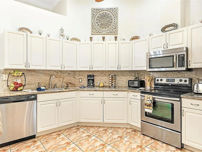 Kitchen with appliances and cabinets stocked with silverware, dishware, and other kitchen items and counter appliances.