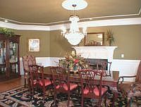 Formal dining room with fireplace, hardwood flooring and wainscoting. 