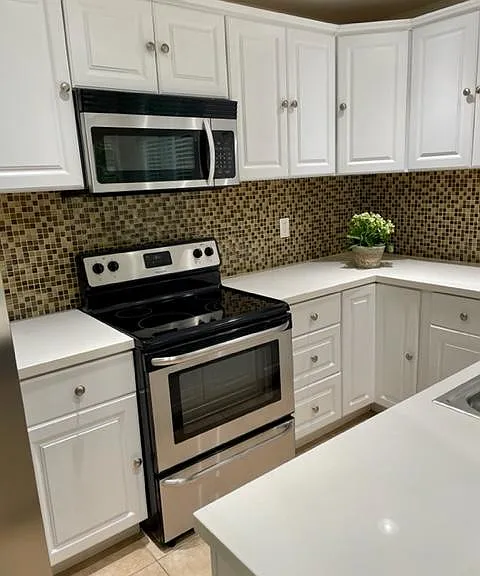 Kitchen view 4 (glass top range and oven and microwave oven). Lower corner cabinets with turntable racks.