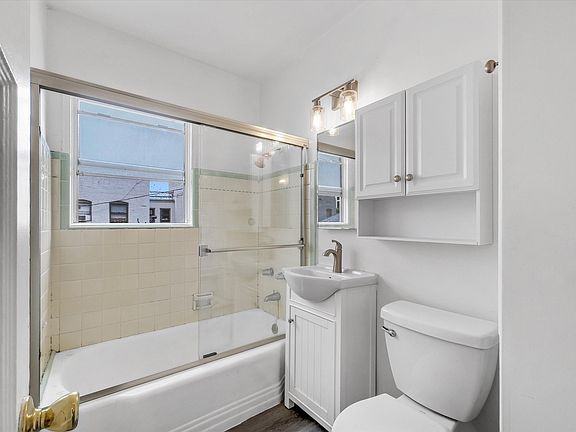 Bathroom with a glass shower door, tub, New vanity, and cabinet.