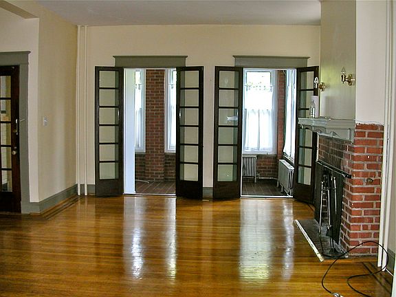 Living room looking onto porch. Front door partially shown on left, fireplace on right.