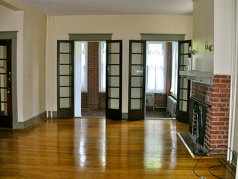 Living room looking onto porch. Front door partially shown on left, fireplace on right.