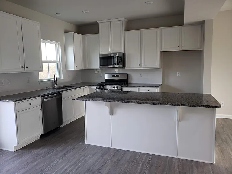 kitchen with granite countertops, island with counter seating, gas stove, and dishwasher