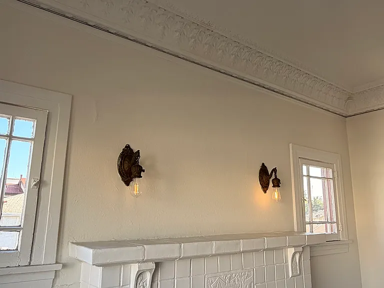 the living room features the original fireplace and crown moulding, and original wall sconces