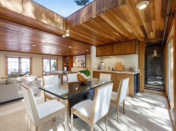 View of the kitchen and sauna from the forest deck across the eating area to the pool area sliding glass doors.