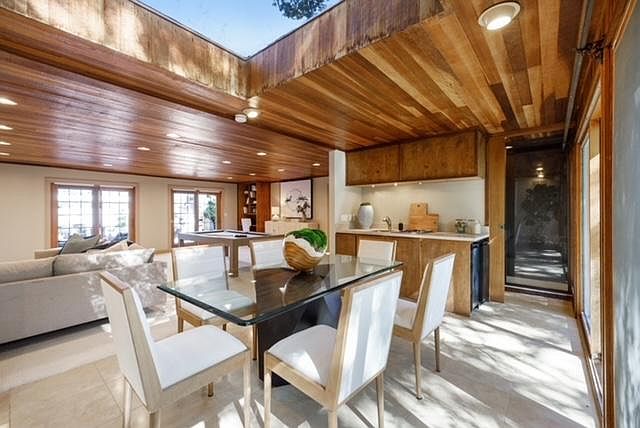 View of the kitchen and sauna from the forest deck across the eating area to the pool area sliding glass doors.