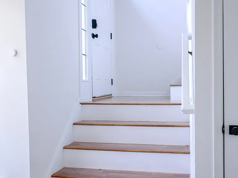 Inviting entryway with natural light and updated hardwood staircase creating a warm first impression.