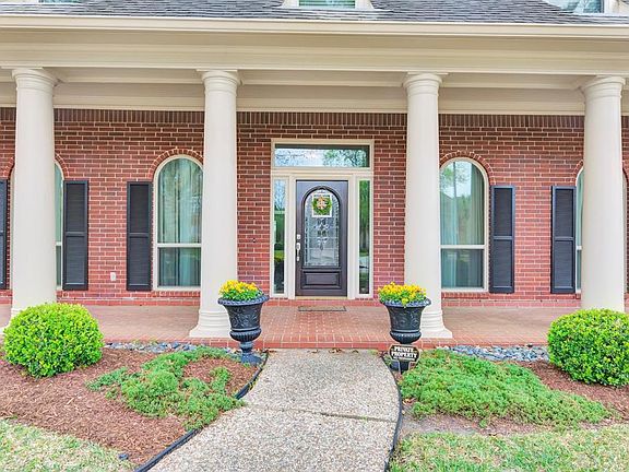Traditional wide brick porch is balanced with tall arched windows and shutters.