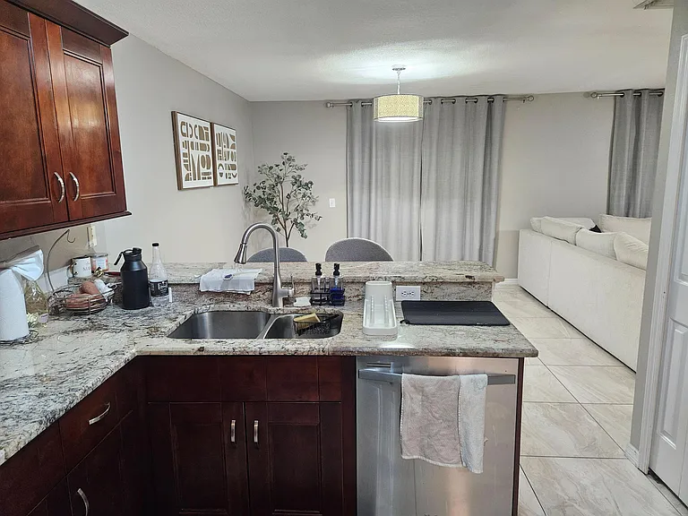 Kitchen with granite counters, breakfast bar seating, and stainless dishwasher, opening to the living area for easy entertain