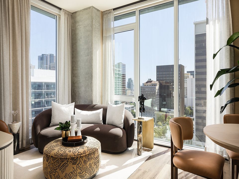 Modern living room with panoramic city views, featuring stylish furniture and abundant natural light.