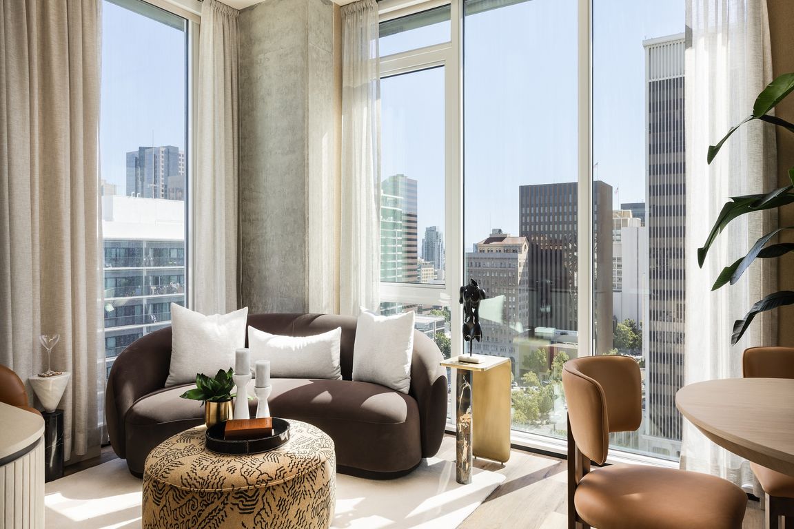 Modern living room with panoramic city views, featuring stylish furniture and abundant natural light.