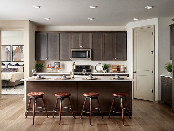 A modern and well-equipped kitchen with dark wood cabinets, a central island with bar stools, and va
