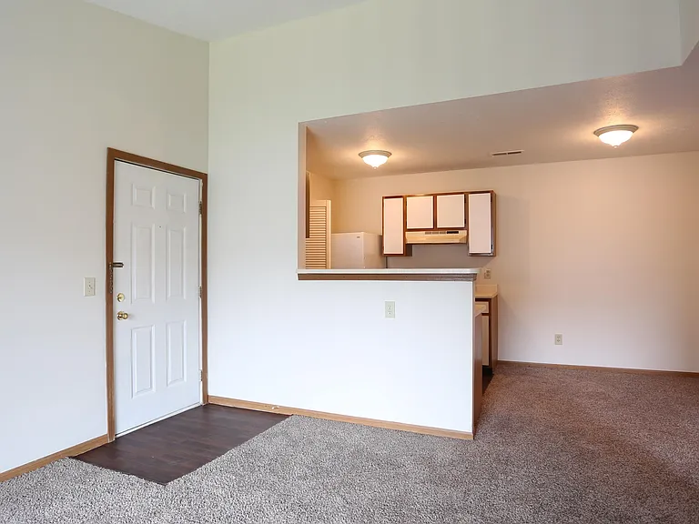 Main living area and kitchen of a River Valley apartment home in Lancaster, OH, with carpeting and cabinets.