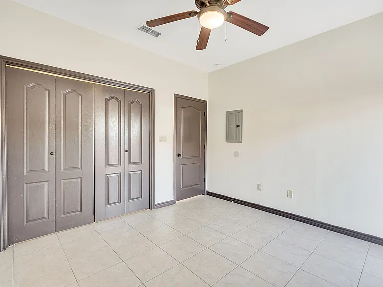 Interior of a room at Merida Vista Apartments with two doors and a ceiling fan, located in Laredo, Texas