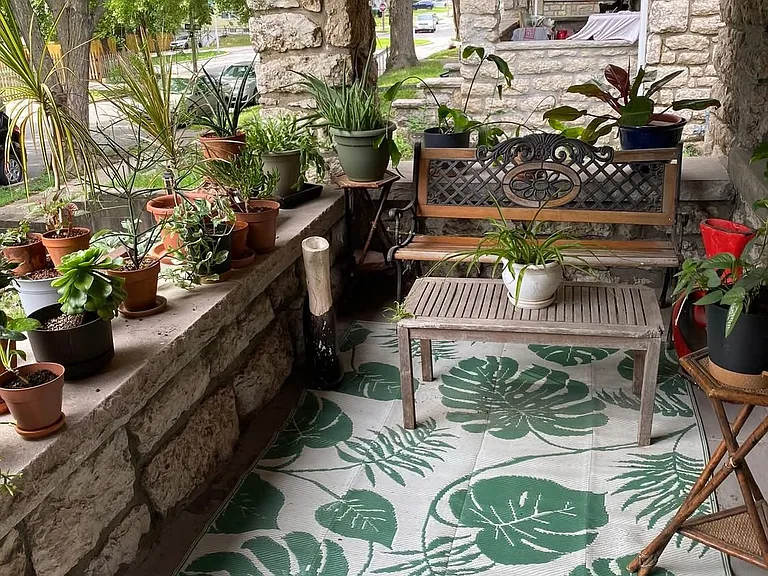 Large front porch, up off the street with a Maple tree shading it and lots of houseplants to make it cozy