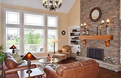 The great room is centered around this beautiful stone fireplace and soaring 22 ft ceilings.  The wall of windows offers a great view of the pond and private back yard.