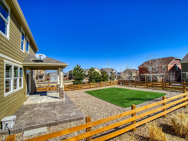 No-maintenance fenced-in backyard with realistic artificial grass, river rock, covered patio, natural gas line for grill, and views of North Table Mountain.