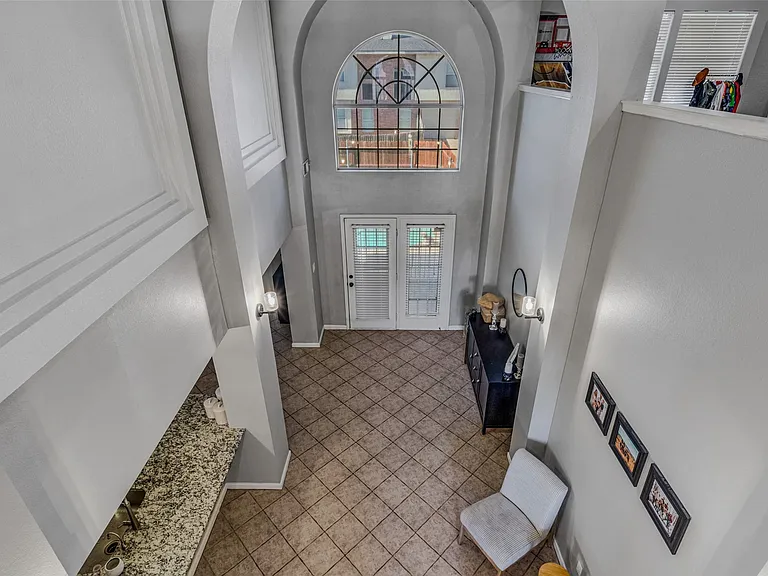 Two-story entry foyer featuring a tiled floor, double glass-paneled entry doors, and an arched window
