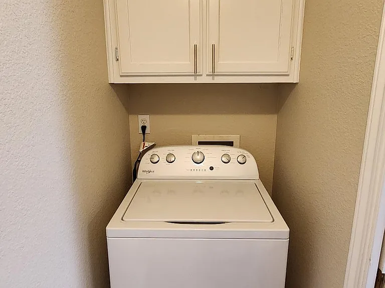 High-capacity washer with cabinets in utility room off the kitchen.