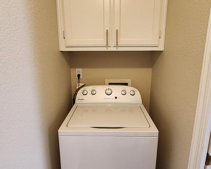 High-capacity washer with cabinets in utility room off the kitchen.
